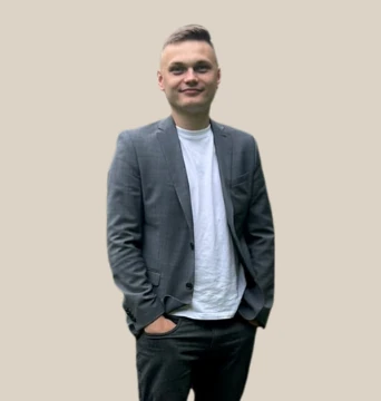 Mateusz Przetocki w marynarce, z rękami w kieszeniach